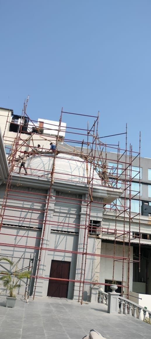 Workers on scaffolding around a white dome on a heritage-style building